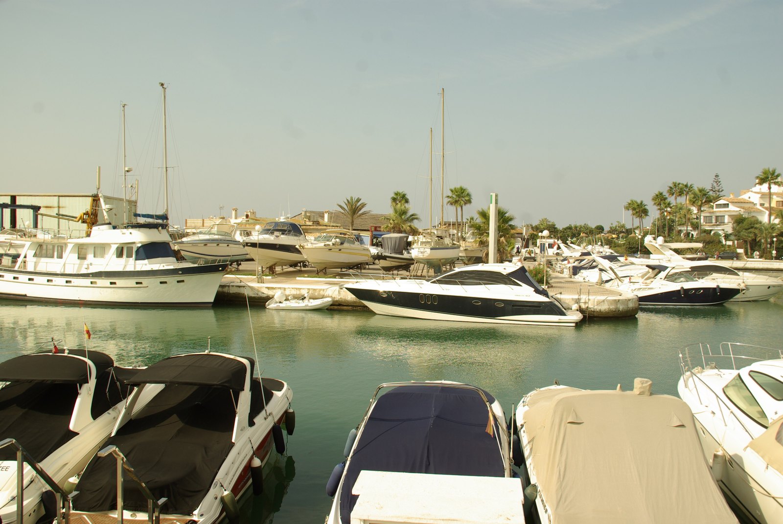 The quayside at Cabopino marina with fishing and leisure boats moored below the stepped village. Photograph: Concepción Amat Orta, CC BY 3.0.