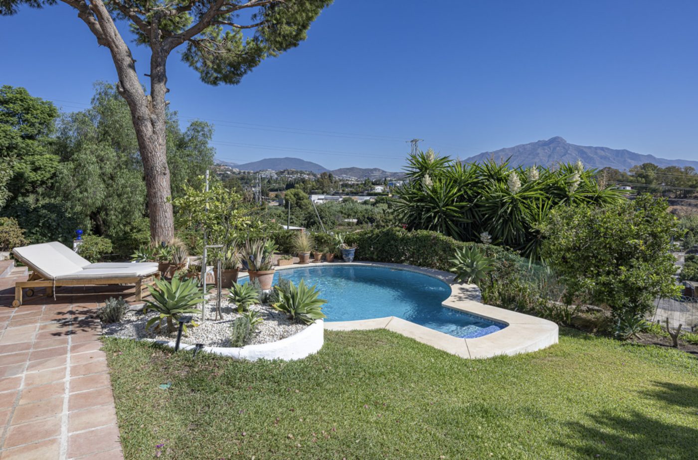 Pool and mature garden of a villa in Guadalmina Alta, the valley and the sierra beyond