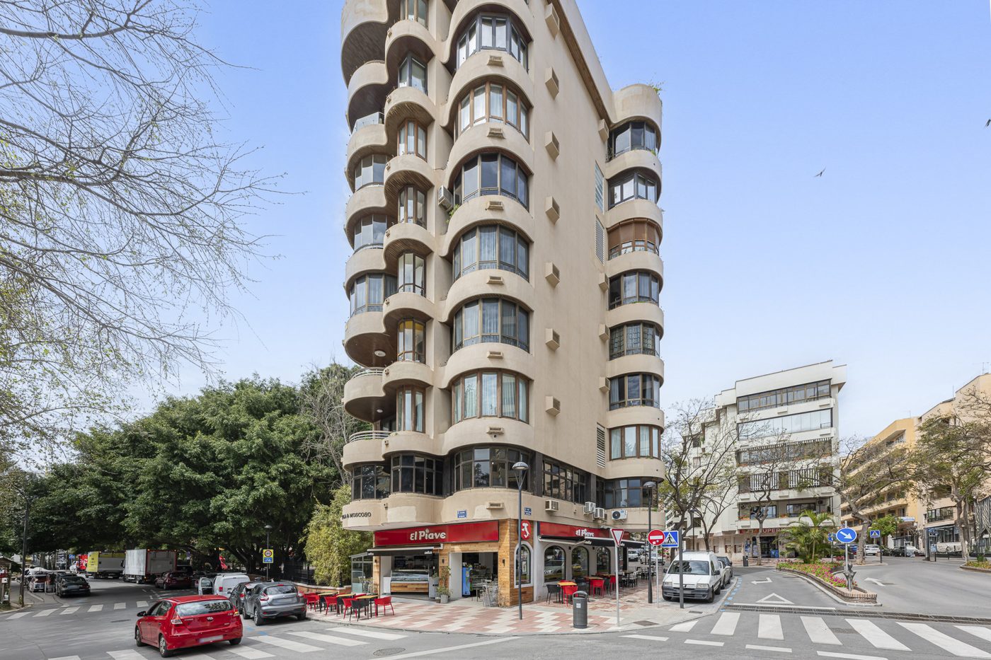 A corner apartment block in central Marbella with shops and a café at street level