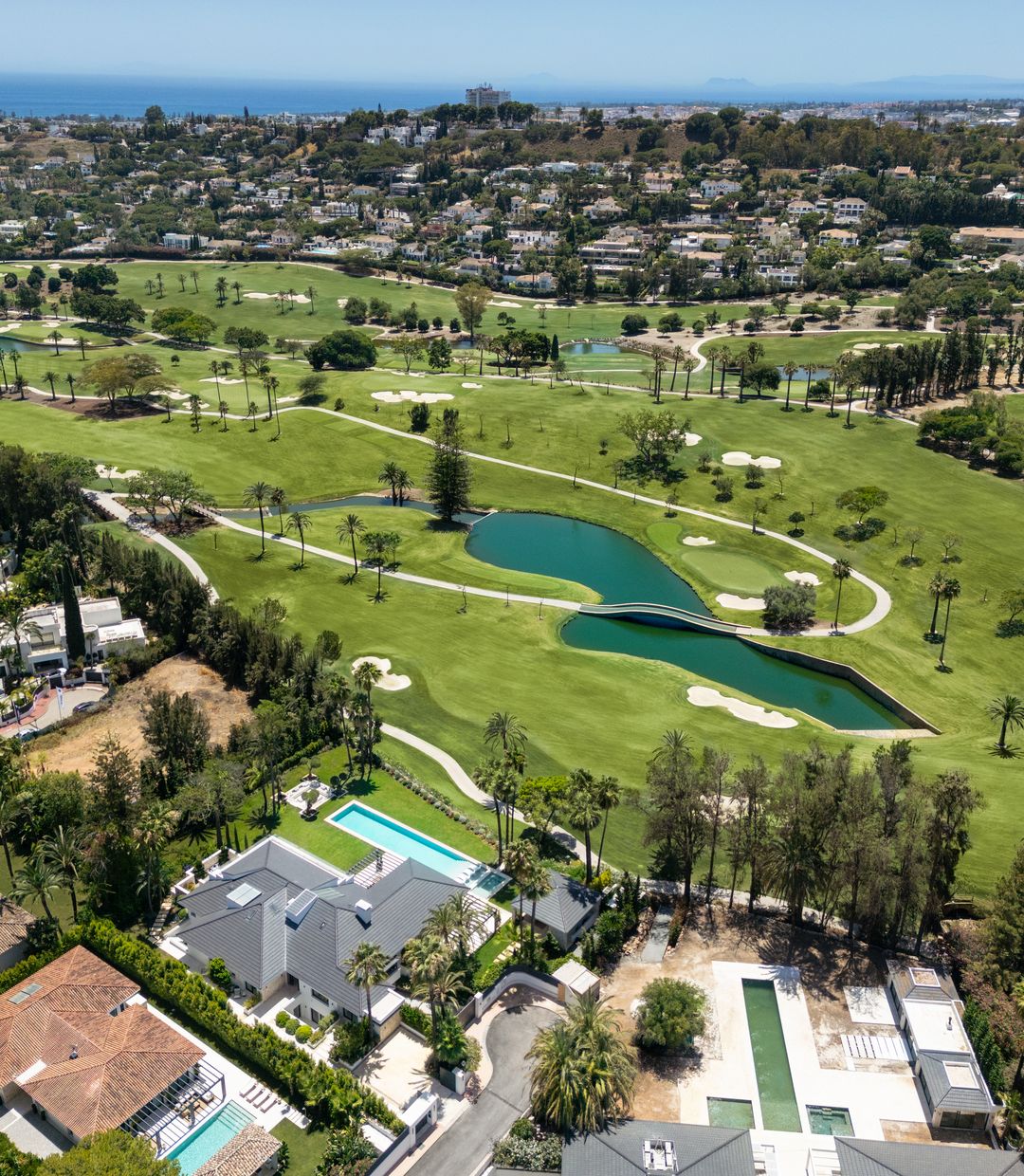 Aerial view over the golf courses of Nueva Andalucia with villas along the fairways and the Mediterranean beyond