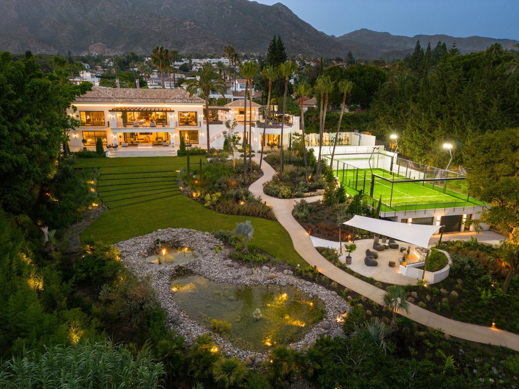 A villa and garden in Nagüeles, Marbella, at dusk with La Concha behind