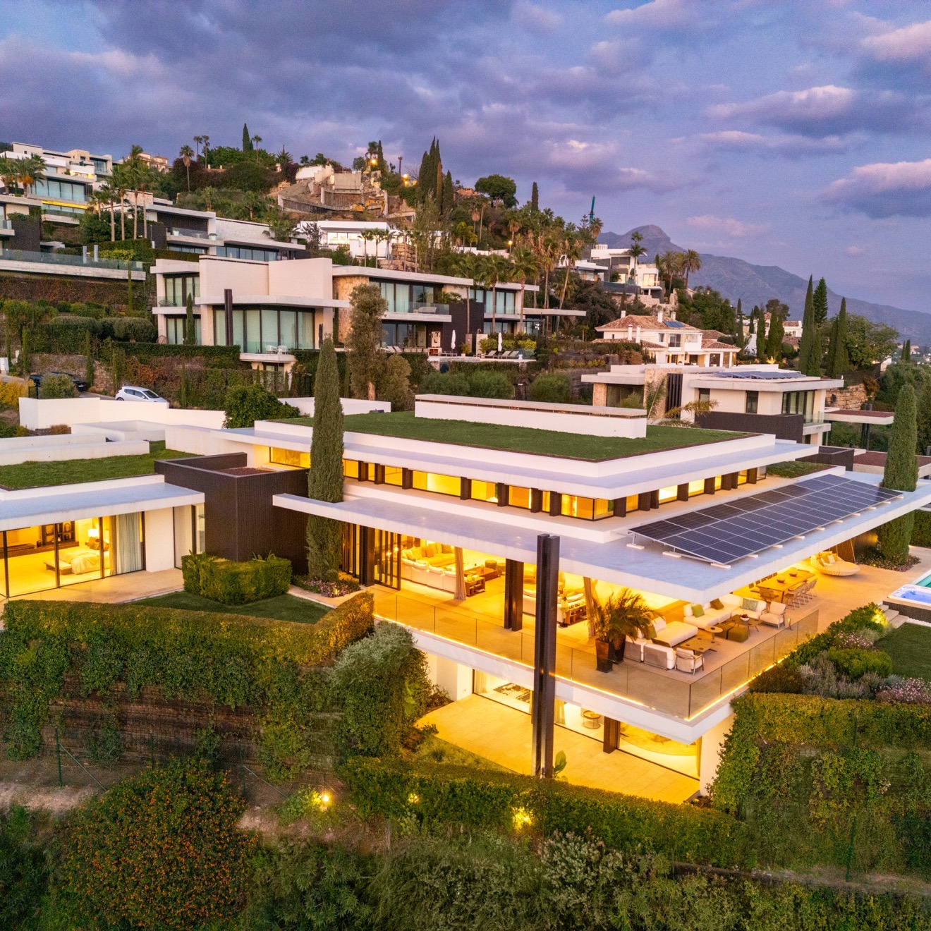 Contemporary hillside villas at dusk on terraced land above Marbella, where landscape and environmental protection overlays apply under the Marbella PGOM