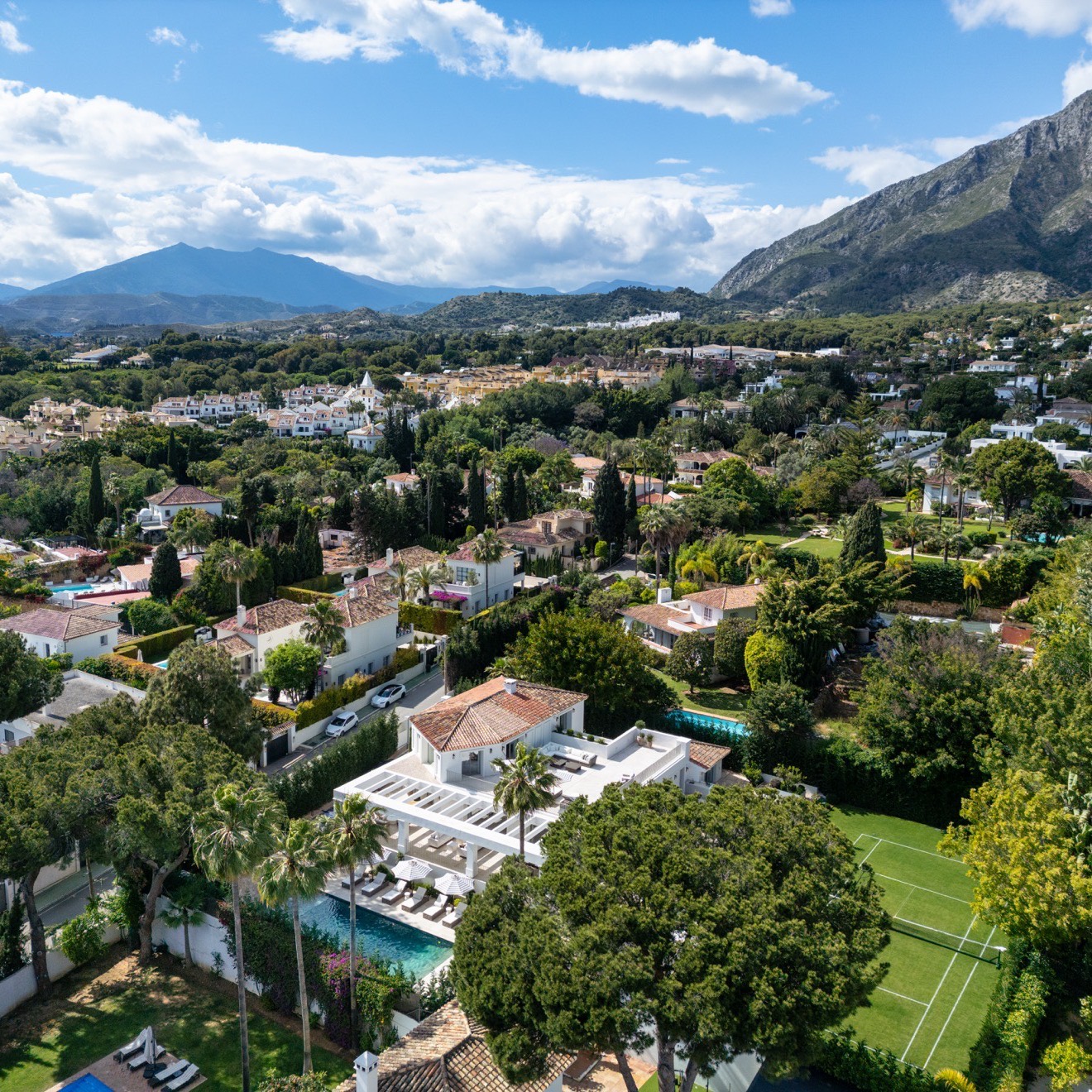 Aerial view of a Marbella residential urbanisation with La Concha and the Sierra Blanca ridge behind, the kind of consolidated urban land classified under the Marbella PGOM