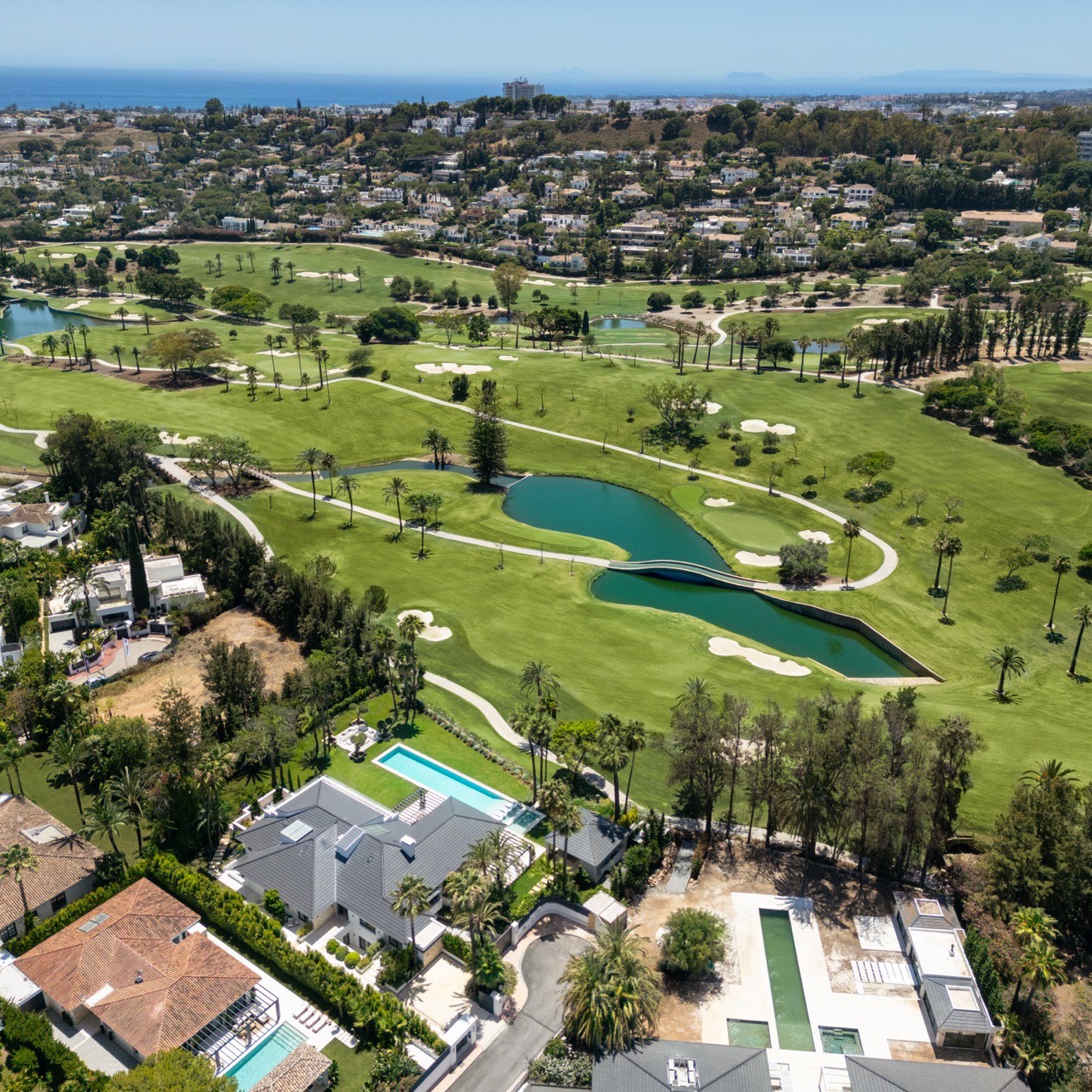 Aerial view of a Marbella golf resort and the villas around it with the coast beyond, an example of the leisure and resort zoning the Marbella PGOM allocates