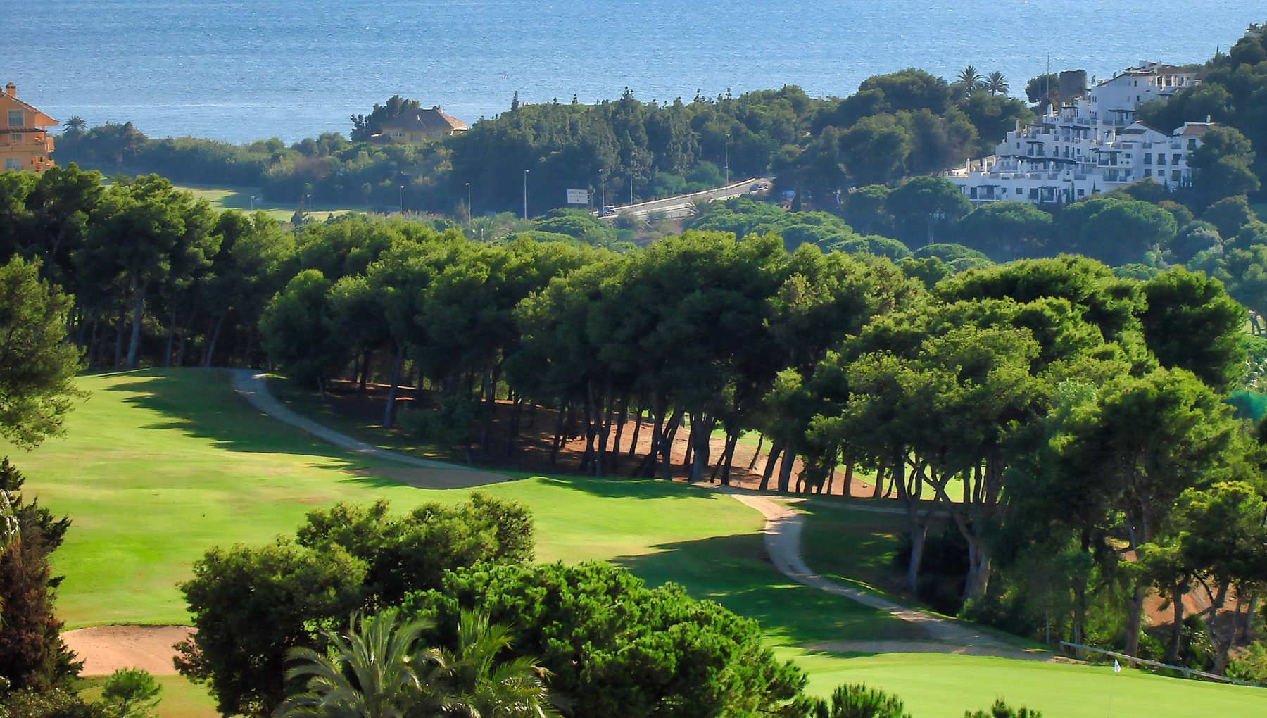A fairway on the Río Real golf course running down through the umbrella pines, the Mediterranean across the top of the valley and white terraces on the ridge beyond