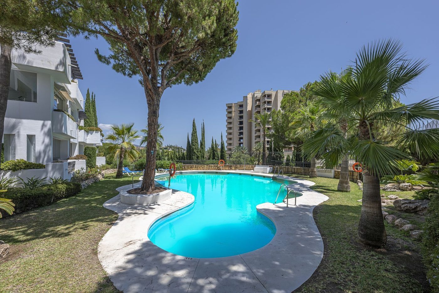 A communal pool and gardens in a gated block at Río Real, the tower block behind