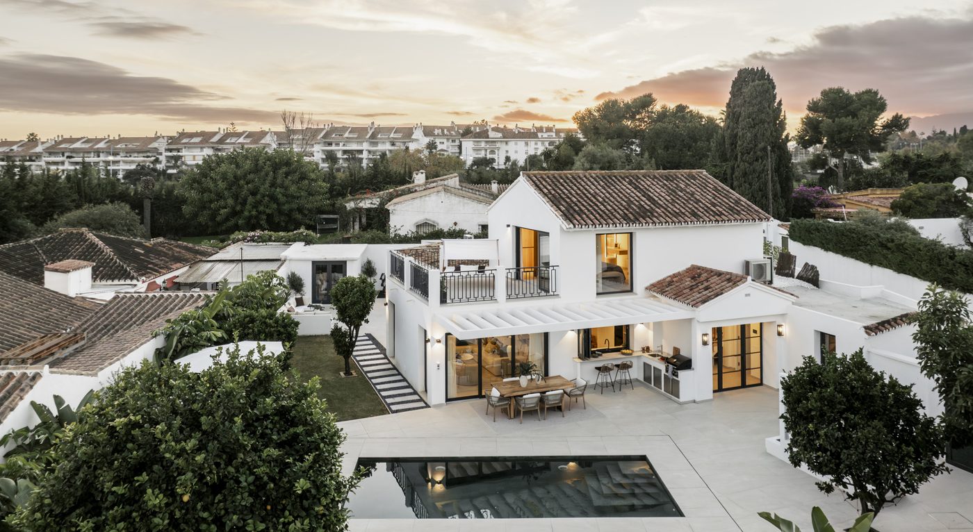 A house and pool in San Pedro de Alcántara at dusk, the low white rooftops of the town behind