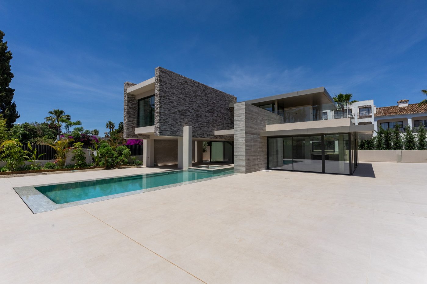 A modern house and pool at Cortijo Blanco in San Pedro de Alcántara, an older villa next door